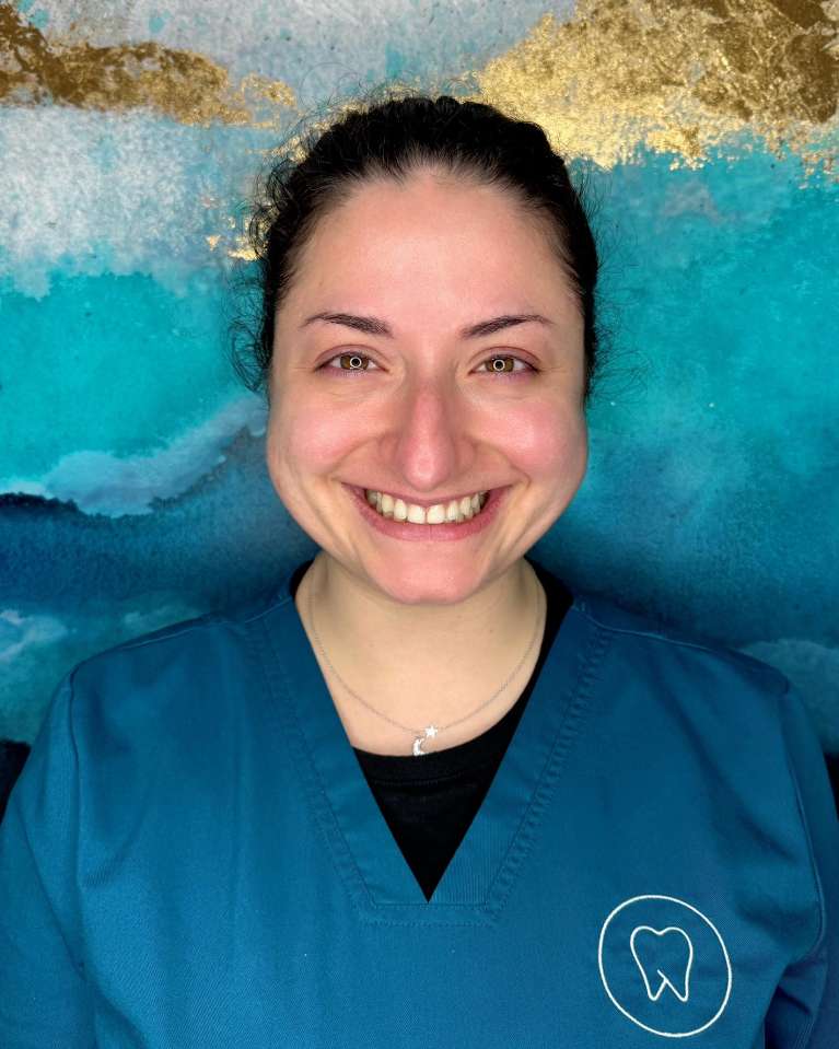 dental assistant with turquoise scrub top and brown curly hair
